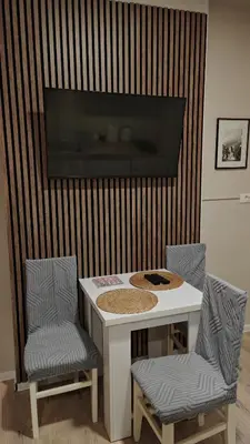 a white table with two chairs and a tv on a wall at AG Cozy Apartment in Belgrade