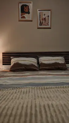 a bed in a bedroom with two pictures on the wall at AG Cozy Apartment in Belgrade