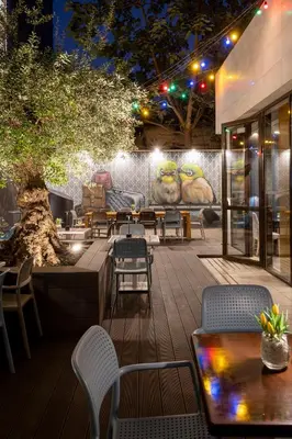 a patio with tables and chairs and a wall with a mural at Nobel Palace Hotel in Belgrade