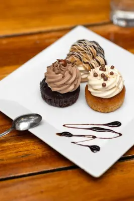 three cupcakes on a white plate with a spoon at Nobel Palace Hotel in Belgrade