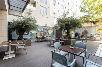 an outdoor patio with tables and chairs and trees at Nobel Palace Hotel in Belgrade