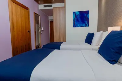 a bedroom with a large bed with blue and white pillows at Nobel Palace Hotel in Belgrade