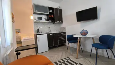 a small kitchen with a table and blue chairs at Center 1 Queen bed Sofa Additional living area in Belgrade