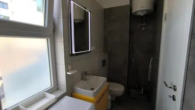a bathroom with a sink and a toilet and a window at Center 1 Queen bed Sofa Additional living area in Belgrade