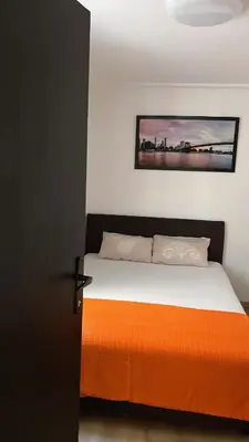 a bedroom with a bed with an orange blanket at Stan ARS in Belgrade