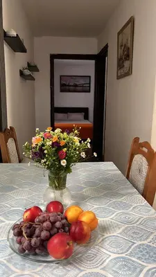 a plate of fruit on a table with a vase of flowers at Stan ARS in Belgrade
