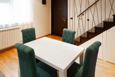 a white table with green chairs in a room at Charming Duplex in Belgrade in Belgrade