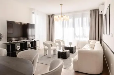 a white living room with white chairs and a tv at Aglaya Paris - Lux 2 Bedroom Apartment in Belgrade