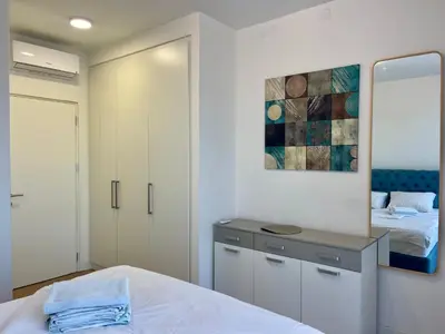 a white bedroom with a bed and a mirror at The Gates 104 in Belgrade