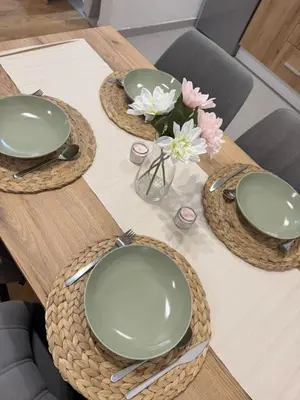 a wooden table with three plates and flowers on it at FlyInn Residence in Belgrade