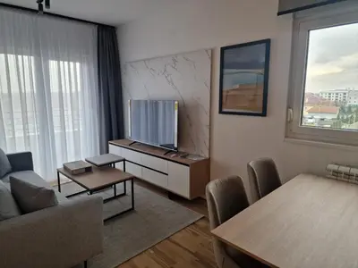 a living room with a tv and a couch and a table at Lux apartman 2 Ledine in Ledine