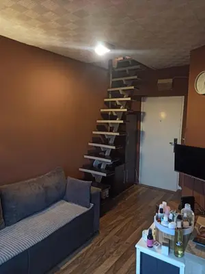 a living room with a couch and a spiral staircase at Stan u centru grada za 2 plus 1 osoba in Belgrade