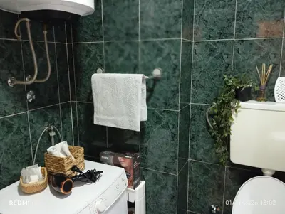 a green tiled bathroom with a toilet and a sink at Apartman Vuk in Obrenovac