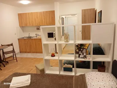 a white book shelf in a room with a kitchen at Apartman Vuk in Obrenovac