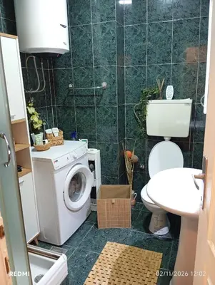 a bathroom with a toilet and a washing machine at Apartman Vuk in Obrenovac
