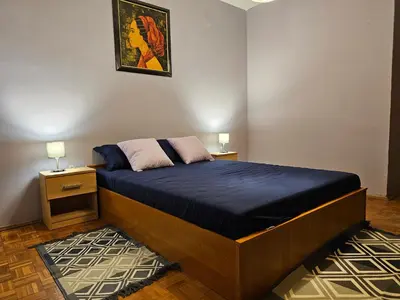 a bedroom with a bed with blue sheets and two lamps at Zante Apartment in Belgrade