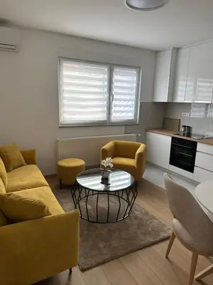 a living room with a table and chairs and a kitchen at Apartman Aranđelovac2 in Arandjelovac