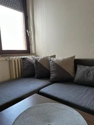 a couch with pillows in a room with a window at Apartment Crystal in Belgrade