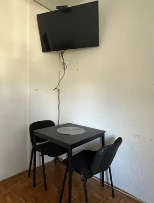 a black table with two chairs and a television on a wall at Apartment Crystal in Belgrade