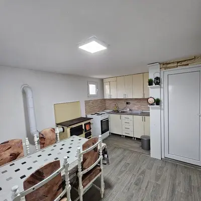 a kitchen with white cabinets and a table in it at Diamond House Rent Vikendica in Beška