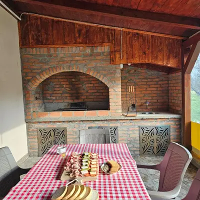 a table with a red and white checkered table cloth and a fireplace at Diamond House Rent Vikendica in Beška