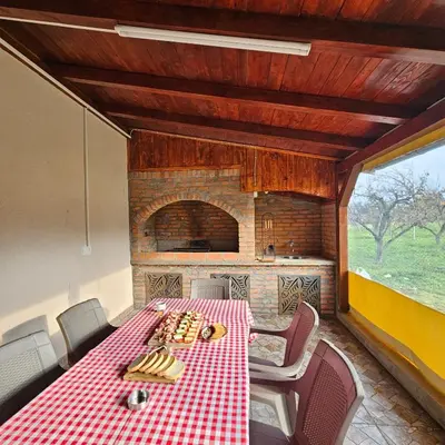 a dining room with a table and a brick oven at Diamond House Rent Vikendica in Beška
