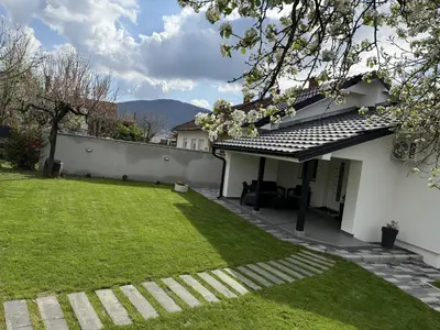 a backyard of a white house with a green lawn at Apartman 28 in Arandjelovac