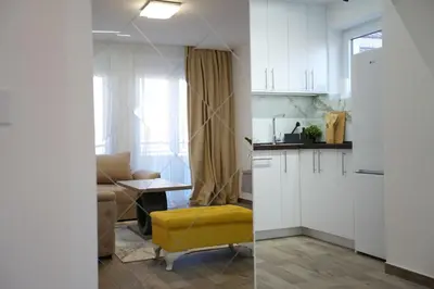 a kitchen with white cabinets and a yellow stool in a room at Apartman 28 in Arandjelovac