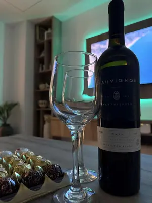 a bottle of wine next to a wine glass and chocolates at Apartman 28 in Arandjelovac