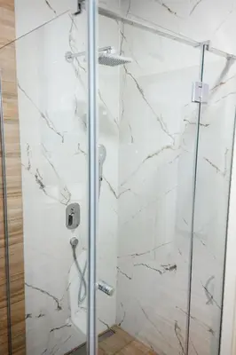 a bathroom with a shower with white marble walls at Tomin sokak Apartment in Belgrade