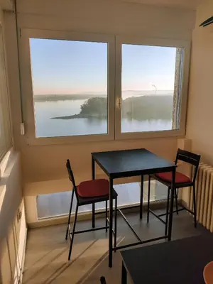 a table and two chairs in a room with a window at Danube Riverview in Belgrade