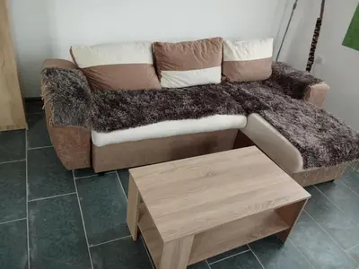 a couch with a blanket and a wooden table at Stan na dan Platičevo in Platičevo