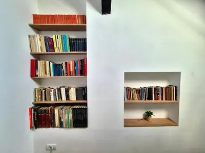 a wall with two shelves filled with books at Roof in Belgrade