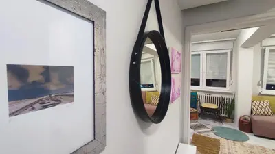 a mirror hanging on a wall in a living room at CoCo Studio Bright & Stylish Apartment in Central Belgrade in Belgrade
