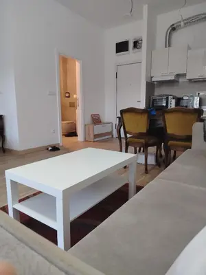 a living room with a white table and a kitchen at Apartman Gala Beograd in Belgrade