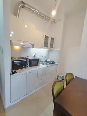 a kitchen with white cabinets and a table with chairs at Apartman Gala Beograd in Belgrade