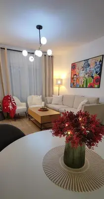 a living room with a white table with a vase with red flowers at EMEM luxury apartment in Belgrade