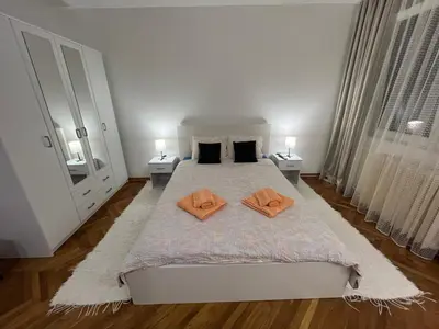 a white bedroom with a bed with two orange towels on it at Apartman Jevtic in Obrenovac