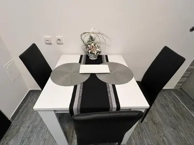 a table with black chairs and a white table with flowers on it at Apartman Jevtic in Obrenovac