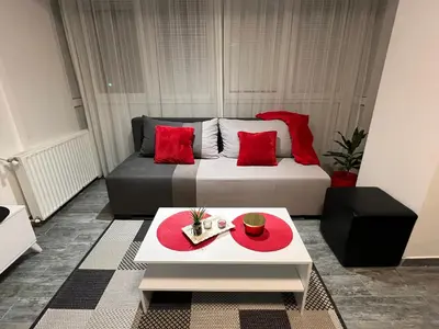 a bedroom with a bed with red pillows and a table at Apartman Jevtic in Obrenovac