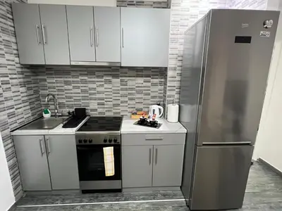 a kitchen with white cabinets and a stainless steel refrigerator at Apartman Jevtic in Obrenovac