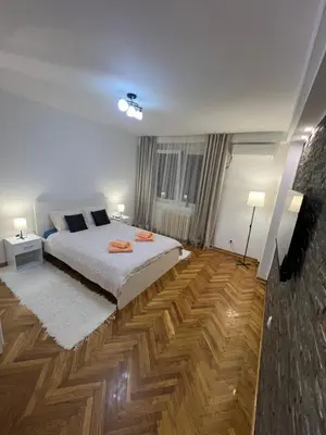 a bedroom with a large bed and wooden floors at Apartman Jevtic in Obrenovac
