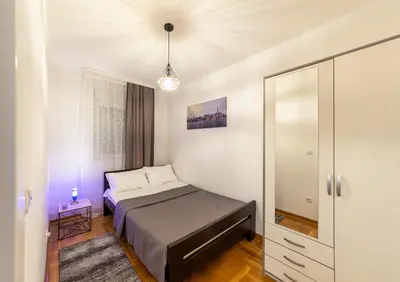 a small bedroom with a bed and a mirror at Apartment SIX - free parking in Belgrade
