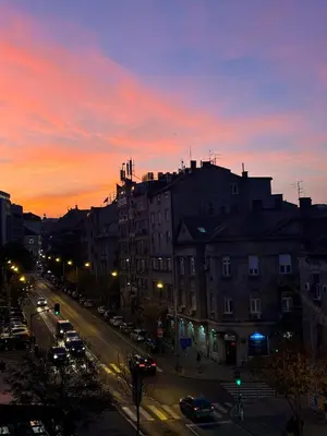 a city street at sunset with cars parked on the street at Beolight Apartment in Belgrade