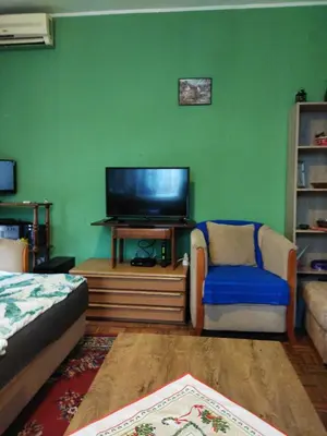 a living room with a flat screen tv and a chair at Grin in Zemun Polje