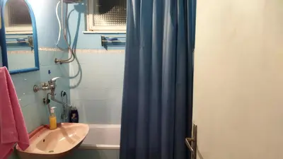a bathroom with a blue shower curtain and a sink at Grin in Zemun Polje