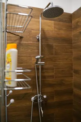 a shower with a shower head on a wooden wall at Atelier in Belgrade