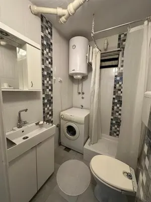 a bathroom with a toilet sink and a washing machine at City Centre Retreat Pionir Apartment in Belgrade