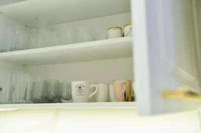 a white shelf with cups and mugs on it at Casa Novi Dorcol Belgrade in Belgrade