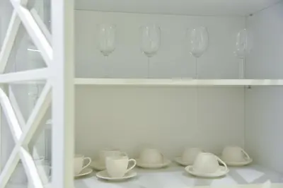 a row of white cups and saucers on a shelf at Casa Novi Dorcol Belgrade in Belgrade